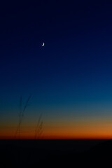 Fototapeta na wymiar Tiny crescent moon in the blue sky just after sunset