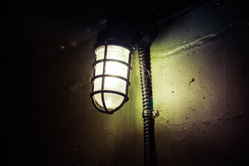 An old WWII era light illuminating the dark with cob webs.