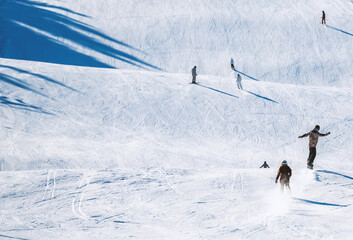 Skiers riding down a slope on a sunny day at a ski resort.
