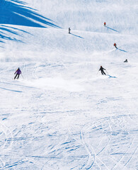 Skiers riding down a steep slope at a winter sports holiday resort.