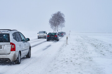 Autos auf Schneebedeckter Straße bei Schneesturm im Winter