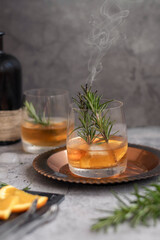 Fototapeta na wymiar Alcoholic drink with sliced orange and steaming rosemary
