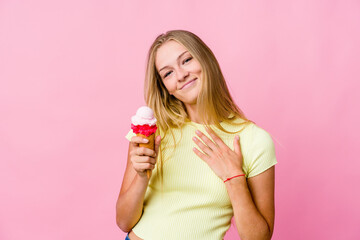 Young russian woman eating an ice cream isolated has friendly expression, pressing palm to chest. Love concept.