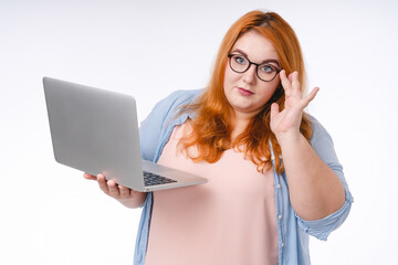 Smart corpulent redhead woman using laptop isolated in white