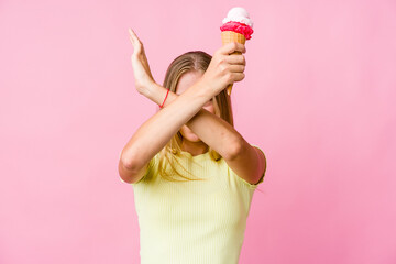 Young russian woman eating an ice cream isolated keeping two arms crossed, denial concept.