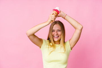 Young russian woman eating an ice cream isolated celebrating a special day, jumps and raise arms with energy.