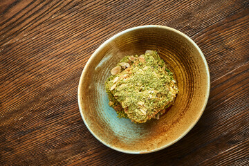 A mouth-watering slice of French dessert mille-feuille with ayers of puff pastry and vanilla slice or custard slice, pistachios. served in plate on wooden background. Napoleon cake