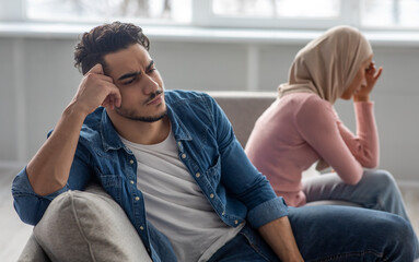Upset man sitting by his crying wife