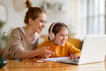 Happy mother supporting daughter during online studies