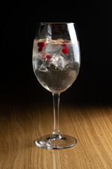 Alcoholic cocktail Spritz with cranberries and ice in a tall transparent wine glass on a wooden table