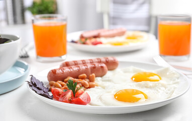 Delicious breakfast with fried eggs and sausages served on white table, closeup