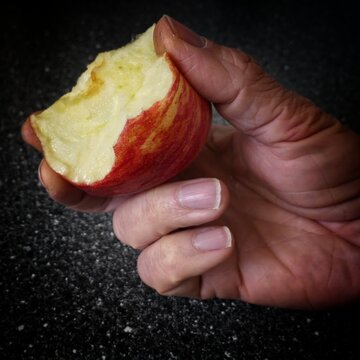 Ein angebissener Apfel der Sorte Gala in einer Männerhand