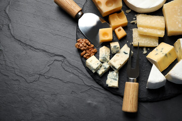 Fototapeta na wymiar Flat lay composition with different sorts of cheese and knives on black table. Space for text