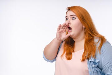 Fat woman with ginger hair announcing with the hand to make it louder isolated over white background