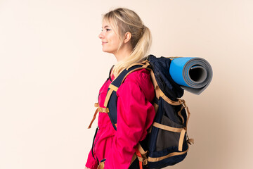 Mountaineer woman with a big backpack over isolated background looking to the side