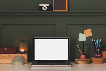 Home office desk against dark wall, laptop, frame and tea light lantern. Cozy workspace.	
