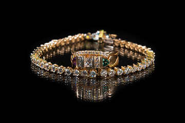 Diamond tennis bracelet and wedding ring on a black reflective background