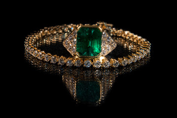 Emerald ring and diamond tennis bracelet on black background 