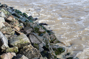 Breakwater. Stones by the sea. Boulders. Rocks by the ocean.