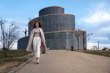 Modelo femenino en un atardecer de invierno en un parque de ciudad con un abrigo beige y ropa de...