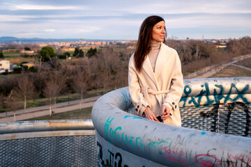 Modelo femenino en un atardecer de invierno en un parque de ciudad con un abrigo beige y ropa de...