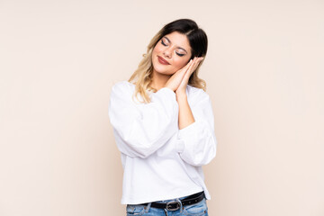Teenager girl isolated on beige background making sleep gesture in dorable expression