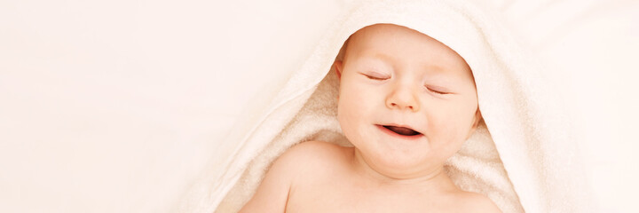 Cute small boy lying at bed. Childhood bath concept. Light background. Little child. Serious emotion. Copyspace. Stay home. Towel mockup. Closed eyes. Horizontal banner