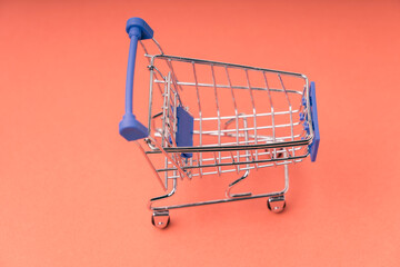 An empty shopping cart on a red scarlet background. Shopping, online shopping concept, copy space, top view