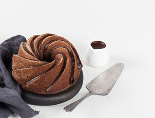 Chocolate round cupcake with icing, sauce and serving spatula on a white background