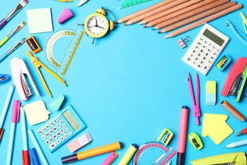 Frame of different stationery on light blue background, flat lay with space for text. Back to school
