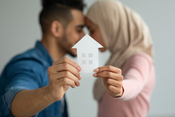 Young loving muslim couple holding paper house