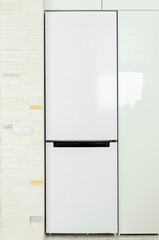 White refrigerator built into the kitchen unit. Close-up, vertical photography.