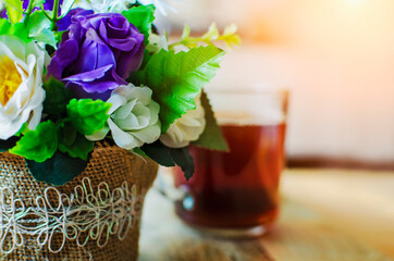 Decoration of artificial flowers against the background of a blurred cup of tea.