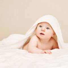 Cute small boy lying at bed. Childhood bath concept. Light background. Little child. Serious emotion. Copyspace. Stay home. Towel mockup