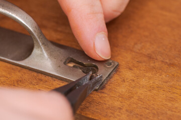 Human hand removing frayed old slotted screw with tongs