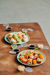 Sushi set on table in office. Party of friends eating sushi rolls using bamboo sticks. Corporate