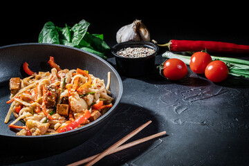 Udon stir-fry noodles with shrimp and vegetables in wok pan on dark background. Appetizing asian cuisine