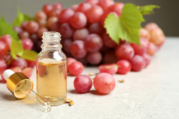 Natural grape seed oil and fresh berries on light table, space for text. Organic cosmetic