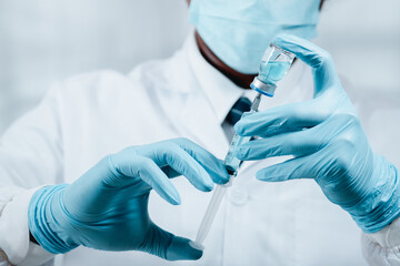A doctor or scientist in the COVID-19 medical vaccine research and development laboratory holds a syringe with a liquid vaccine to study and analyze antibody samples for the patient.