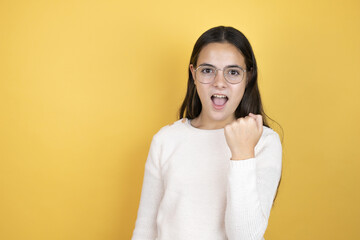 Beautiful child girl wearing casual clothes angry and mad raising fist frustrated and furious while shouting with anger. Rage and aggressive concept.