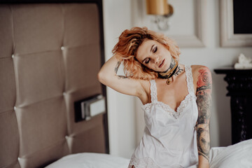 Fototapeta premium Portrait of a happy beautiful girl with tattoos. The woman is lying in bed.