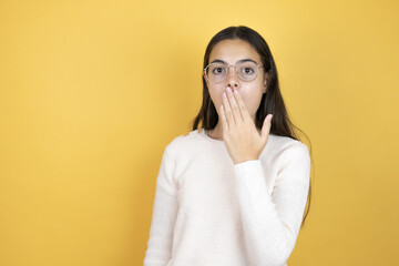 Beautiful child girl wearing casual clothes covering mouth with hand, shocked and afraid for mistake. surprised expression