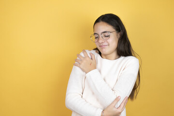 Beautiful child girl wearing casual clothes hugging oneself happy and positive, smiling confident