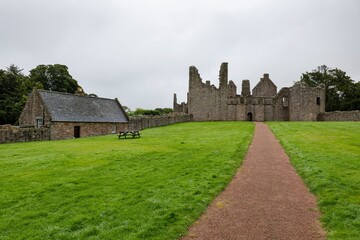 Fototapeta na wymiar The pathway and green lawn of Tolquhon Castle in Tarves, Ellon, Scotland in overcast weather