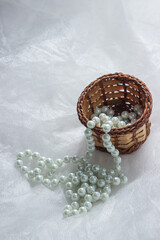 Pearl necklace on a white surface. modern costume jewelry in delicate colors on crumpled fabric.