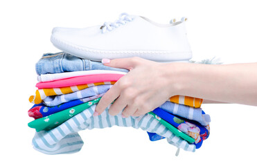 Stack folded colorful clothing with white sneakers in hand on white background isolation