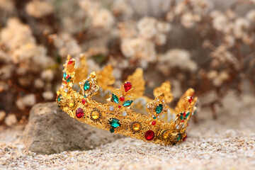 Beautiful golden crown on sand outdoors, closeup. Fantasy item