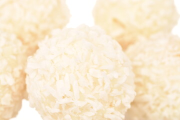 Several round sweets with coconut flakes, close-up, isolated on white.