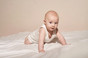 Cute small boy lying at bed. Childhood concept. Light background. Serious child. Copyspace. Stay...