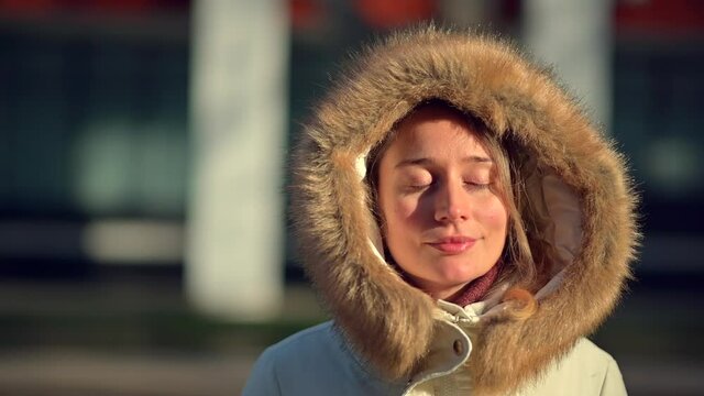Happy woman wearing white winter coat  resting outside in the sun